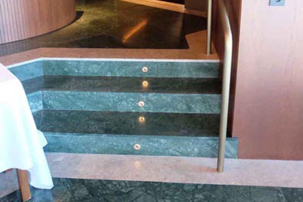 Stairs with a handrail to access the tables with sea views.