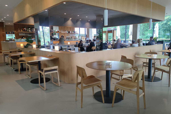 Vue panoramique générale de la cafétéria avec le comptoir et les différents types de tables.