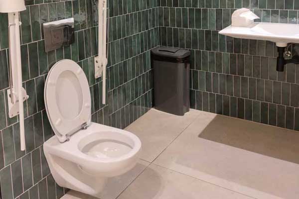 Wash-hand basin and toilet bowl in the public toilets on level -1, with a foldaway bar.