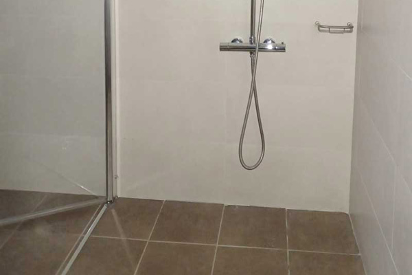 Douche affleurante dans la salle de bain de la chambre adaptée.