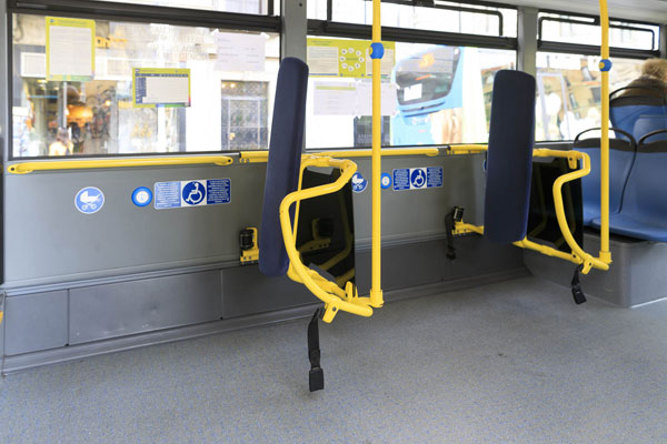 Dos zonas en el interior del autobús para personas usuarias de silla de ruedas y carros de niños. Señalización vertical, pictogramas azules.