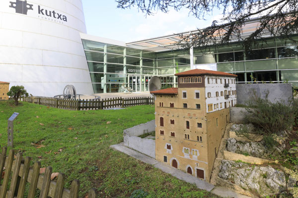 Entrada y zona exterior del Museo de la Ciencia, rodeado por un pequeño jardín y maquetas de edificios representativos de Gipuzkoa.