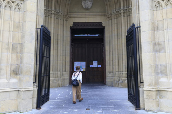 Acceso a la entrada de la Catedral del Buen Pastor a través de dos puertas metálicas negras abiertas.