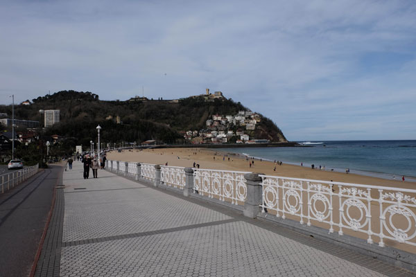 
Walk along the beach of Ondarreta. Railing on the right and Mount Igueldo in the background. 