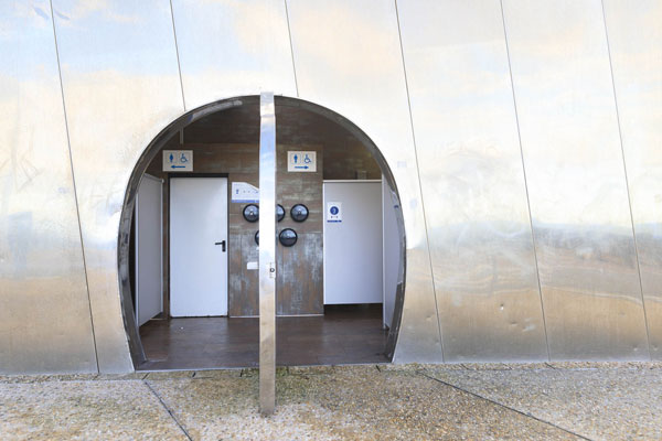 Puerta de acceso a los aseos públicos del paseo nuevo de San Sebastián. Señalización de accesibilidad en la entrada.